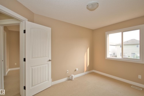 Neutral-toned room with beige carpeting, white baseboards, and a white window frame - 11513 17 Avenue, Edmonton, AB 
