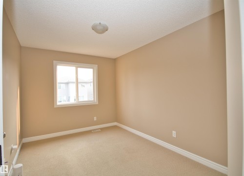 Neutral-toned room featuring a single window, textured ceiling, and carpeted flooring - 11513 17 Avenue, Edmonton, AB 