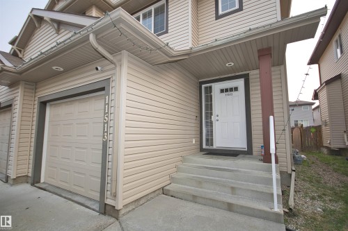 Front exterior featuring light-toned horizontal siding and a panel-style garage door - 11513 17 Avenue, Edmonton, AB 