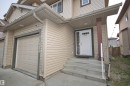 Front exterior featuring light-toned horizontal siding and a panel-style garage door - 11513 17 Avenue, Edmonton, AB 