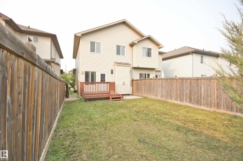Spacious backyard featuring a wooden deck with railing, a grass lawn, and full privacy fencing - 11513 17 Avenue, Edmonton, AB 