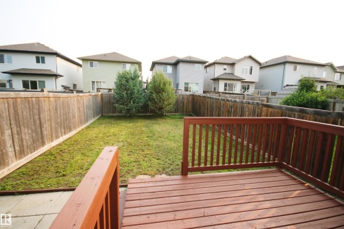 Spacious backyard featuring a wooden deck, natural wood privacy fencing, and a grassy lawn with mature plantings - 11513 17 Avenue, Edmonton, AB 