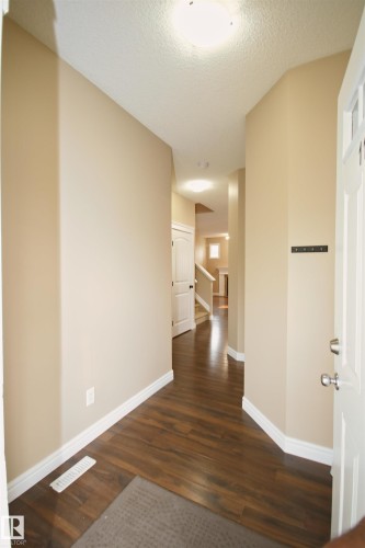 Entryway featuring wood-finish flooring, neutral wall tones, white baseboards, and a contemporary flush-mount ceiling light - 11513 17 Avenue, Edmonton, AB 
