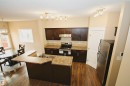 Kitchen featuring dark wood cabinetry, a stainless steel range, and a coordinating refrigerator - 11513 17 Avenue, Edmonton, AB 