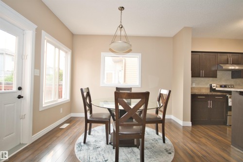 Open concept dining area with wood-finish flooring, neutral wall tones, and white trim - 11513 17 Avenue, Edmonton, AB 