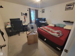 Bedroom space featuring light-colored carpeting, a window with dark curtains, and a ceiling-mounted light fixture - 