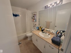 Bathroom featuring a vanity with a light-toned countertop, integrated sink, and white cabinetry - 