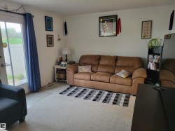 Carpeted living area featuring a glass-paned exterior door, built-in wall decor, and neutral wall tones - 