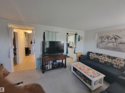 Carpeted living area featuring white walls and a textured ceiling - 