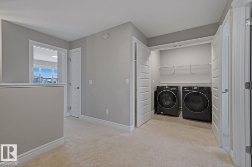 Dedicated laundry closet featuring a front-loading washer and dryer set, tiled flooring, and wire shelving - 1364 Keswick Drive Sw, Edmonton, AB 