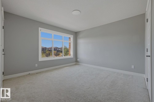 Spacious room with light gray wall paint and light-toned carpet - 1364 Keswick Drive Sw, Edmonton, AB 