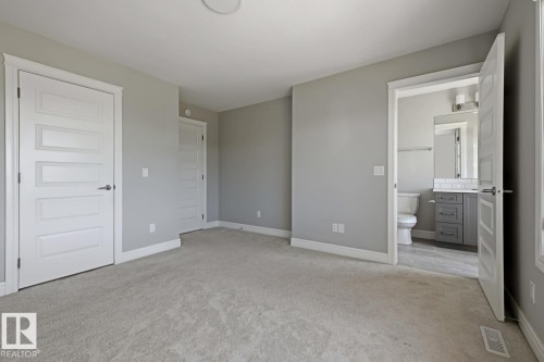 Bedroom featuring light gray carpeting, neutral wall paint, and white trim - 1364 Keswick Drive Sw, Edmonton, AB 