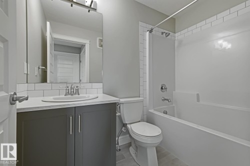 Full bathroom featuring a vanity with a white countertop, undermount sink, and dark cabinetry - 1364 Keswick Drive Sw, Edmonton, AB 