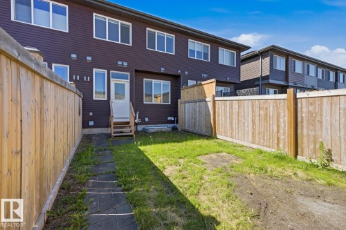 Private backyard featuring a wooden fence, paver stone pathway, and direct access to the dwelling - 1364 Keswick Drive Sw, Edmonton, AB 