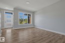 Wood-finish flooring throughout, complemented by a modern front door with frosted glass panels and a transom window - 1364 Keswick Drive Sw, Edmonton, AB 