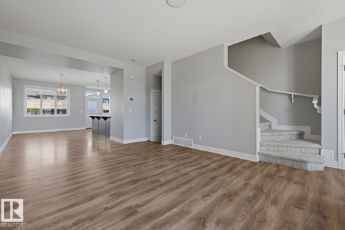 Open-concept living area featuring wood-finish flooring, light grey wall paint, and white baseboards - 1364 Keswick Drive Sw, Edmonton, AB 