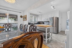Open-concept kitchen and dining area featuring white cabinetry, stainless steel appliances, and a butcher block island - 