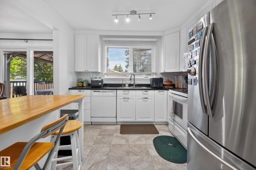 Modern kitchen featuring white cabinetry, dark countertops, and stainless steel appliances - 18509 92A Avenue, Edmonton, AB 