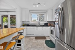 Modern kitchen featuring white cabinetry, dark countertops, and stainless steel appliances - 
