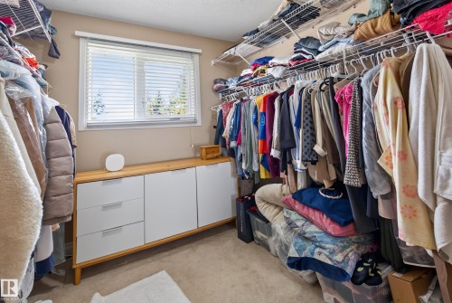 Walk-in closet featuring wire shelving, built-in cabinetry with light wood-finish top, and a window with blinds - 18509 92A Avenue, Edmonton, AB 