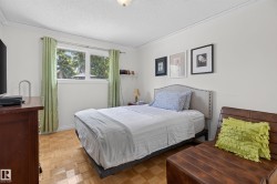 Spacious room featuring wood-finish parquet flooring, white crown molding, and a large window with green tree views - 