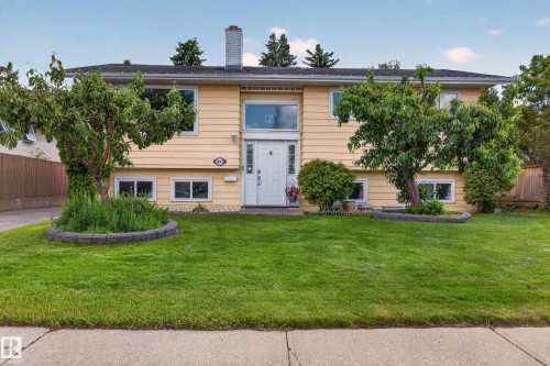 Split-level residence featuring a pale yellow exterior and a prominent white front door with sidelights - 18509 92A Avenue, Edmonton, AB 