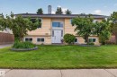 Split-level residence featuring a pale yellow exterior and a prominent white front door with sidelights - 18509 92A Avenue, Edmonton, AB 