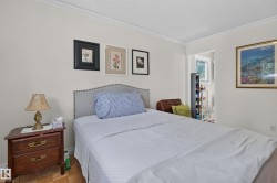 Bedroom featuring a light-colored accent wall, crown molding, and wood-finish flooring - 