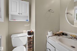 Bathroom featuring a white vanity cabinet with an integrated sink, a circular wall mirror, and a wall-mounted towel ring - 