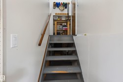 Interior staircase featuring gray-painted wooden treads and a natural wood handrail - 
