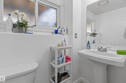 Pedestal sink with chrome faucet, frosted window with white trim, and a wall-mounted mirror - 