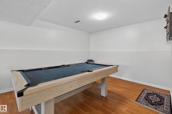Recreation room featuring wood-finish flooring, two-tone painted walls, and a ceiling-mounted light fixture - 