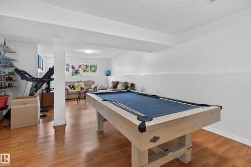 Spacious recreation room featuring wood-finish flooring and bright white walls - 18509 92A Avenue, Edmonton, AB 