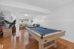 Spacious recreation room featuring wood-finish flooring and bright white walls - 