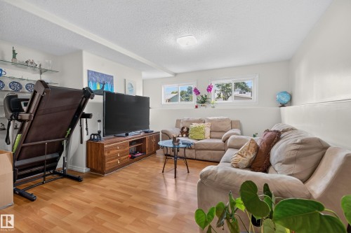 Spacious room featuring wood-finish flooring, light-colored walls, and a textured ceiling - 18509 92A Avenue, Edmonton, AB 