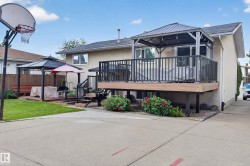 Rear exterior featuring a multi-level deck, a lower patio with a gazebo, a concrete driveway, and a basketball hoop - 