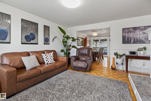 Living area featuring neutral wall tones, a flat white ceiling, and a fireplace with a stone-finish hearth - 18509 92A Avenue, Edmonton, AB 
