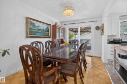 Dining area featuring wood-finish parquet flooring, a decorative overhead light fixture, and a sliding glass door providing access to an exterior deck - 