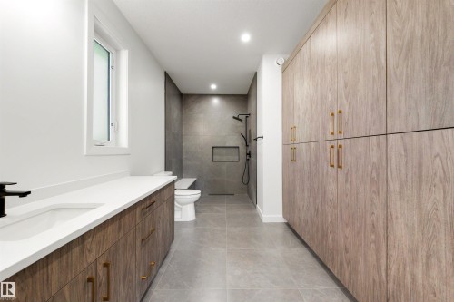 Spacious bathroom featuring a double vanity with wood-finish cabinetry, white countertop, and a built-in sink - 39 Elsinore Place, Edmonton, AB 