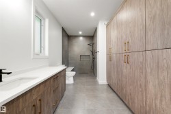 Spacious bathroom featuring a double vanity with wood-finish cabinetry, white countertop, and a built-in sink - 