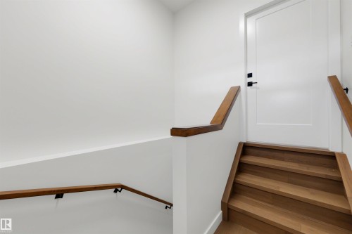 Staircase featuring wood-finish treads and risers, complemented by a solid wood handrail with matte black brackets - 39 Elsinore Place, Edmonton, AB 