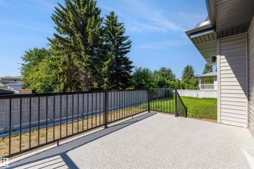Rear deck with a textured concrete surface and black metal railings - 39 Elsinore Place, Edmonton, AB 