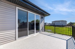 Outdoor balcony featuring a textured gray surface, black metal railings, and sliding glass doors with an integrated screen door - 
