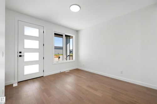 Entryway featuring a modern door with four frosted glass panels, matte black hardware, and wood-finish flooring - 39 Elsinore Place, Edmonton, AB 