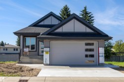 Modern exterior with a light gray garage door featuring frosted glass panels, dark gray siding, a dark shingle roof, and an inviting concrete driveway - 