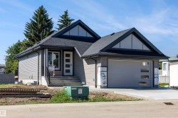 Contemporary home with gabled rooflines, dark asphalt shingles, and light gray horizontal siding - 
