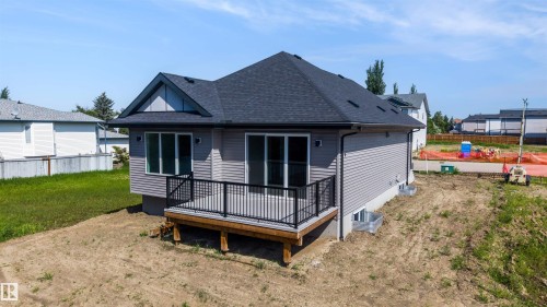 Newly constructed property featuring light gray siding, a dark asphalt shingle roof, and a rear wood deck with black metal railings - 39 Elsinore Place, Edmonton, AB 