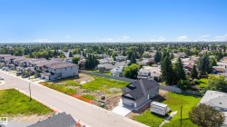 Newly constructed residence featuring a gray exterior, dark shingle roof, and an attached garage with a concrete driveway - 