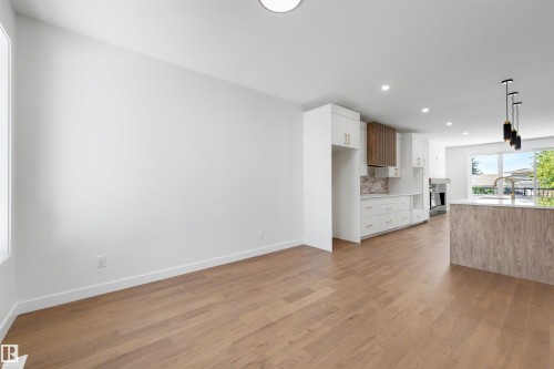 Open-concept living area featuring light wood-finish flooring, white walls, recessed lighting, and a modern kitchen - 39 Elsinore Place, Edmonton, AB 