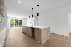 Open-concept kitchen featuring a large center island with a white countertop and wood-finish cabinetry - 